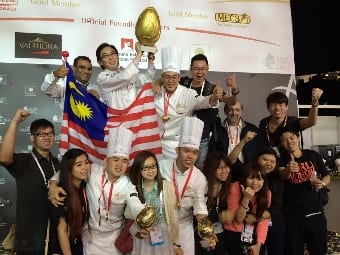 The winning Asian Pastry Cup 2014 team of (front row 3rd and 5th left respectively) Chef de Partie Tay Chee Siang of the Kuala Lumpur Convention Centre and Pastry Chef Tan Wei Loon and (top row, 3rd left) Executive Pastry Chef Chiam Ko Seen from the Academy of Pastry Arts Malaysia, together with Chef Chern Chee Hong, President of Chefs Association of Malaysia, and their assistants and supporters give their victory the thumbs up.